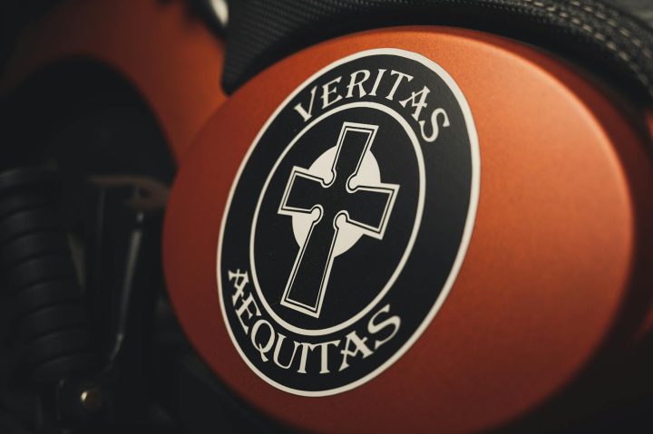 Artistic close-up of a Veritas Aequitas emblem on a motorcycle, featuring a cross design.